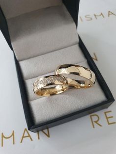 two gold wedding rings sitting in a box