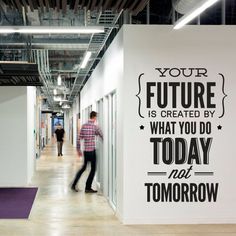 a man walking down a hallway next to a white wall with a quote on it that says your future is created by what you do today not tomorrow