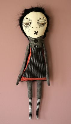 a creepy doll hanging on the wall in front of a pink wall with black and white stripes