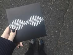 a person holding up a black box with white sound waves on it