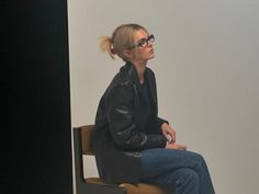 a woman sitting on top of a chair with her hair in a pony tail bun