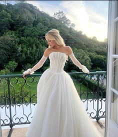 a woman in a wedding dress standing on a balcony