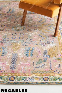 an area rug with a yellow chair and colorful floral design on the bottom, in front of a white wall