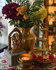 there is a vase with flowers in it on the table next to candles and other items