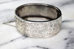 Antique sterling silver hinged bangle bracelet from the late Victorian Era. The front is hand engraved with swirling ivy leaves. The design extends a little bit to the back side of the bracelet for a little extra detail. Era: Victorian Markings: None Material: Sterling Silver (acid tested) Measurements: 24.5 mm wide 58mm x 46.2mm Condition: Good antique condition with minor wear from age. A few dings and dents on the back. Hinge works well. Safety chain is intact. Shipping is free in the United Ivy Leaves, Almandine Garnet, Sterling Silver Locket, Garnet Bracelet, Ivy Leaf, Safety Chain, Silver Lockets, Hinged Bangle, Heart Locket