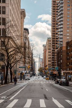 an empty city street with tall buildings on both sides and people walking across the street