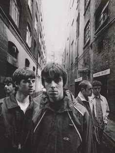 black and white photograph of young men walking down an alleyway in the city, looking at camera