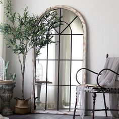 a room with a chair, mirror and potted plant