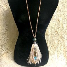 a mannequin with a necklace on it and a tassel hanging from the neck