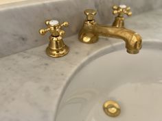 two golden faucets are sitting on a marble sink