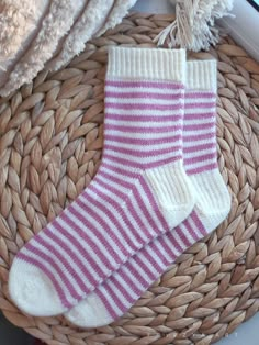 two pairs of pink and white socks sitting on top of a basket next to a pile of towels