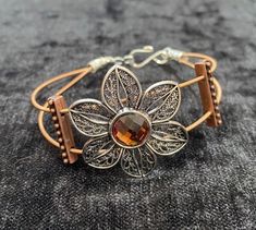 a close up of a bracelet with a flower on it