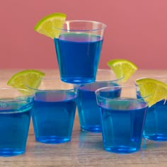 several glasses filled with blue liquid and lemon wedges