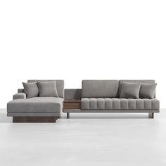 a gray couch with pillows on it in front of a white wall