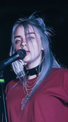 a woman with blue hair singing into a microphone