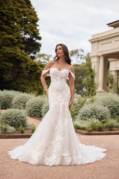 a woman in a wedding dress posing for the camera with her hands on her hips