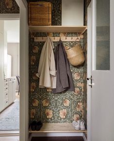 an open closet with clothes hanging on the wall next to shoes and baskets in it