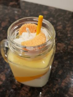 a glass jar filled with orange slices and ice cream on top of a marble counter