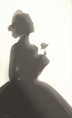 the silhouette of a woman in a dress holding a flower