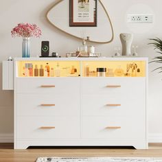 a white dresser sitting in a living room next to a potted plant