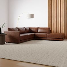 a brown leather couch sitting on top of a white rug in a living room next to a lamp