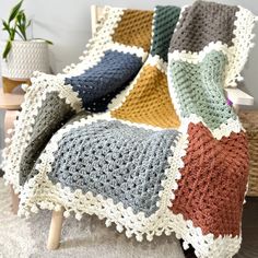 a crocheted blanket sitting on top of a chair next to a potted plant