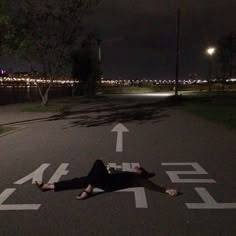 a person laying on the ground in an empty parking lot at night with no one around