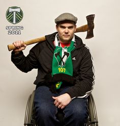 a man sitting in a wheel chair holding a baseball bat and wearing a green scarf