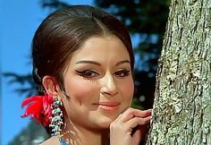 a woman leaning against a tree wearing earrings