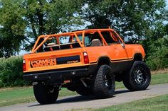 an orange truck parked on the side of a road next to some grass and trees