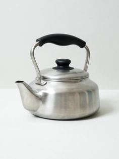 a silver tea kettle with a black handle