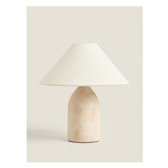 a white table lamp with a beige shade on the base and a light bulb attached to it