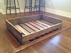 a wooden bed frame sitting on top of a hard wood floor next to bar stools