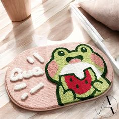 a bathroom rug with an image of a frog holding a watermelon in its mouth