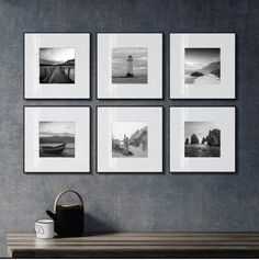 four black and white pictures hanging on the wall above a table with a coffee cup