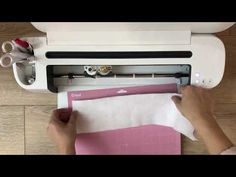 a person is using a machine to cut fabric on a piece of white paper with scissors