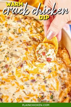 a hand dipping a tortilla chip into a casserole dish with cheese