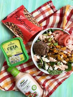 a salad with dressing and other ingredients on a checkered table cloth next to it