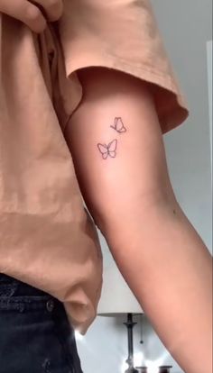 a woman's arm with a small butterfly tattoo on the left side of her arm