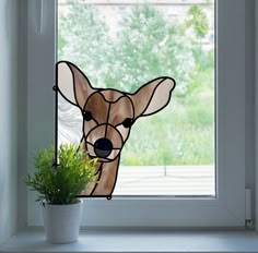 a stained glass window with a deer's head in the center and a potted plant on the other side