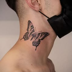 a man's neck with a butterfly tattoo on the back of his neck,