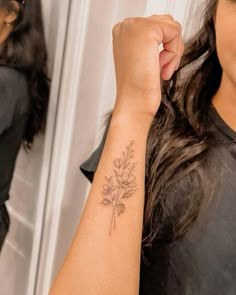 a woman with a flower tattoo on her arm is standing in front of a mirror