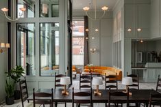 a room with chairs, tables and couches in front of large windows that look out onto the street