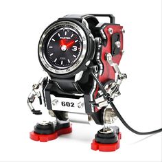 a red and black robot clock sitting on top of a white surface