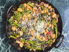 a skillet filled with broccoli, beans and parmesan cheese