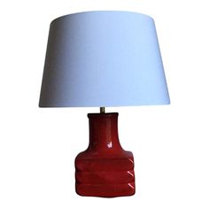 a red ceramic table lamp with a white shade