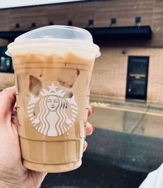 a person holding up a starbucks drink in front of a building