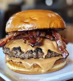 a bacon cheeseburger is sitting on a white plate with brown gravy