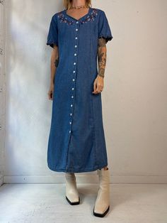 "- Vintage Wardrobe Essentials button up denim dress - Floral embroidery details - Ruffle trim on the sleeves - 100% cotton - Made in China - Tagged 12   Bust: 20.5\" Waist: 19\" Length: 49\"" Button-up Denim Blue Cotton Dress, Denim Blue Cotton Button-up Dress, Spring Denim Dress With Button Closure And Relaxed Fit, Spring Denim Dress With Relaxed Fit And Button Closure, Cotton Denim Midi Dress With Button Closure, Cotton Midi Denim Dress With Button Closure, Elegant Ribbed Collar Top, Button-up Cotton Denim Dress With Pockets, Button-up Denim Dress With Pockets