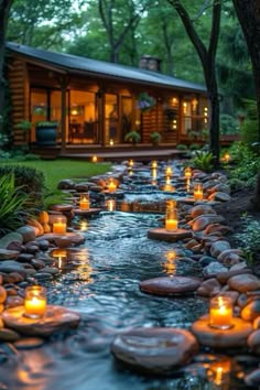 many lit candles are on the rocks in front of a house